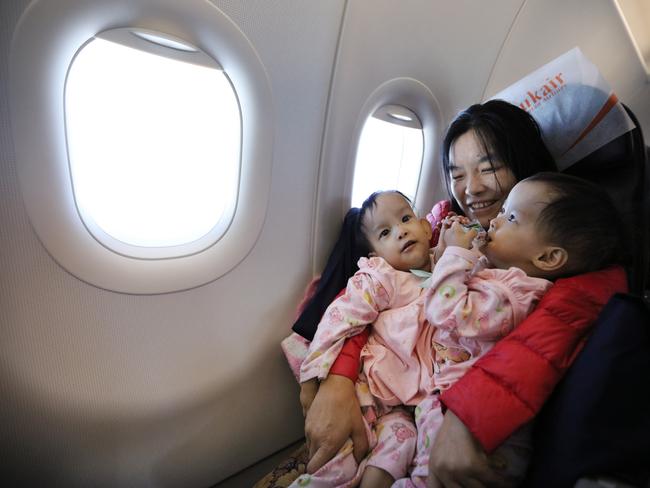 Mum Bhumchu holds Nima and Dawa during the flight from Bhutan to Bangkok. Picture: Alex Coppel