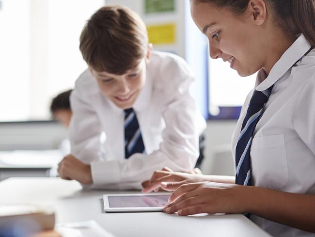 Two High School Students Wearing Uniform Working Together At Desk Using Digital Tablet Picture: Istock