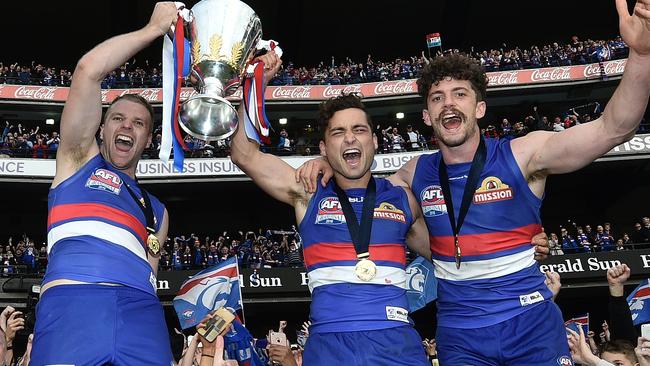 Jake Stringer, Luke Dahlhaus and Tom Liberatore hold the premiership cup. Picture: AAP.