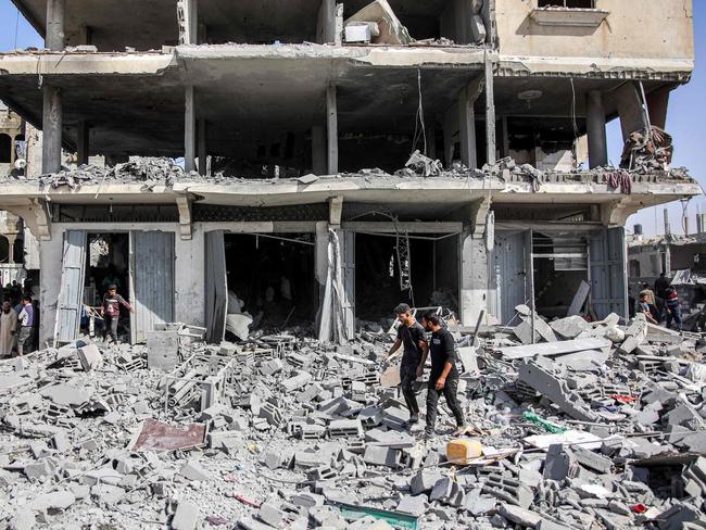 Men walk through rubble following Israeli bombardment on the four-storey Muqat family house in the Zarqa neighbourhood in the north of Gaza City on October 26, 2024 amid the ongoing war in the Palestinian territory between Israel and Hamas. (Photo by Omar AL-QATTAA / AFP)