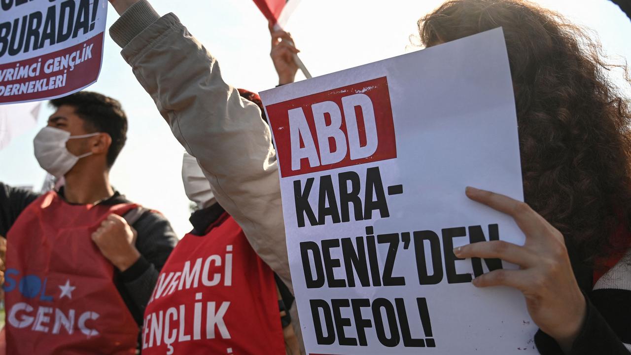 A group of protesters hold placards reading, ‘USA get out from the Black Sea’ near the USS Mount Whitney anchored off the port of Sarayburnu. Picture: Ozan Kose/AFP