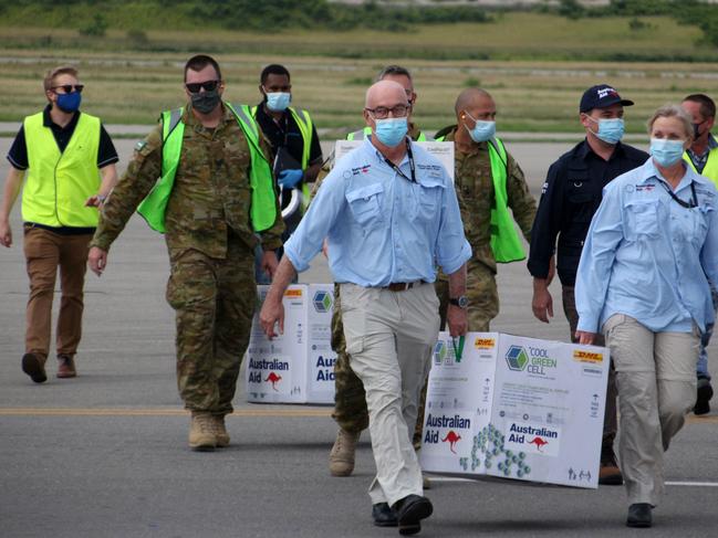 Australian officials carry boxes containing some 8000 initial doses of the AstraZeneca vaccine following their arrival in Papua New Guinea. Picture: AFP