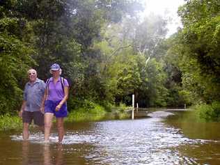 Grays Lane resident Isabel Reed and friend John Payne walk through floodwater to reach Mr Payne’s car after the Tyagarah road was cut. . Picture: Cathy Adams