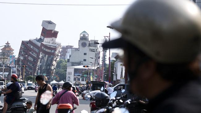 Residents ride past a damaged building in Hualien on Thursday. Picture: AFP