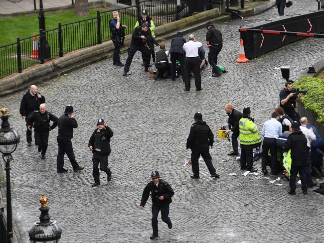 A policeman points a gun at the attacker on the floor as emergency services attend the scene outside the Houses of Parliament, London. Picture: Stefan Rousseau