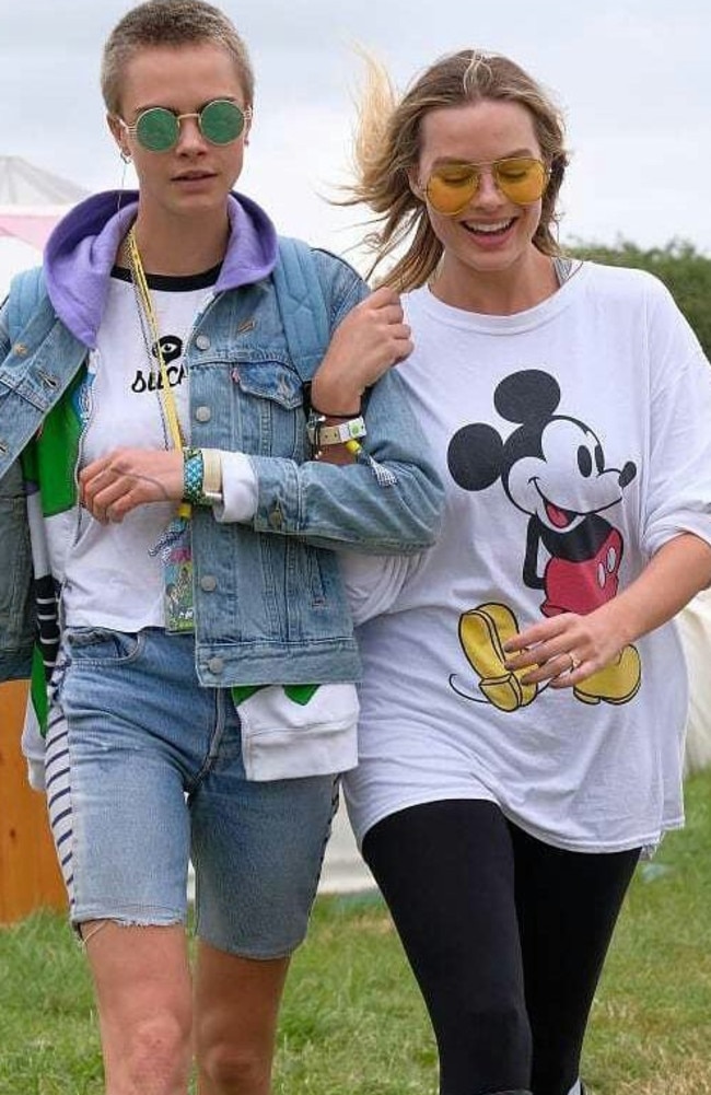 Cara and Margot stroll arm-in-arm around the festival grounds.