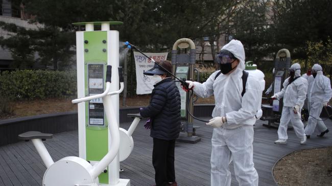 Members of a local residents group wear protective gear as they disinfect a local park in Seoul. Picture: AP