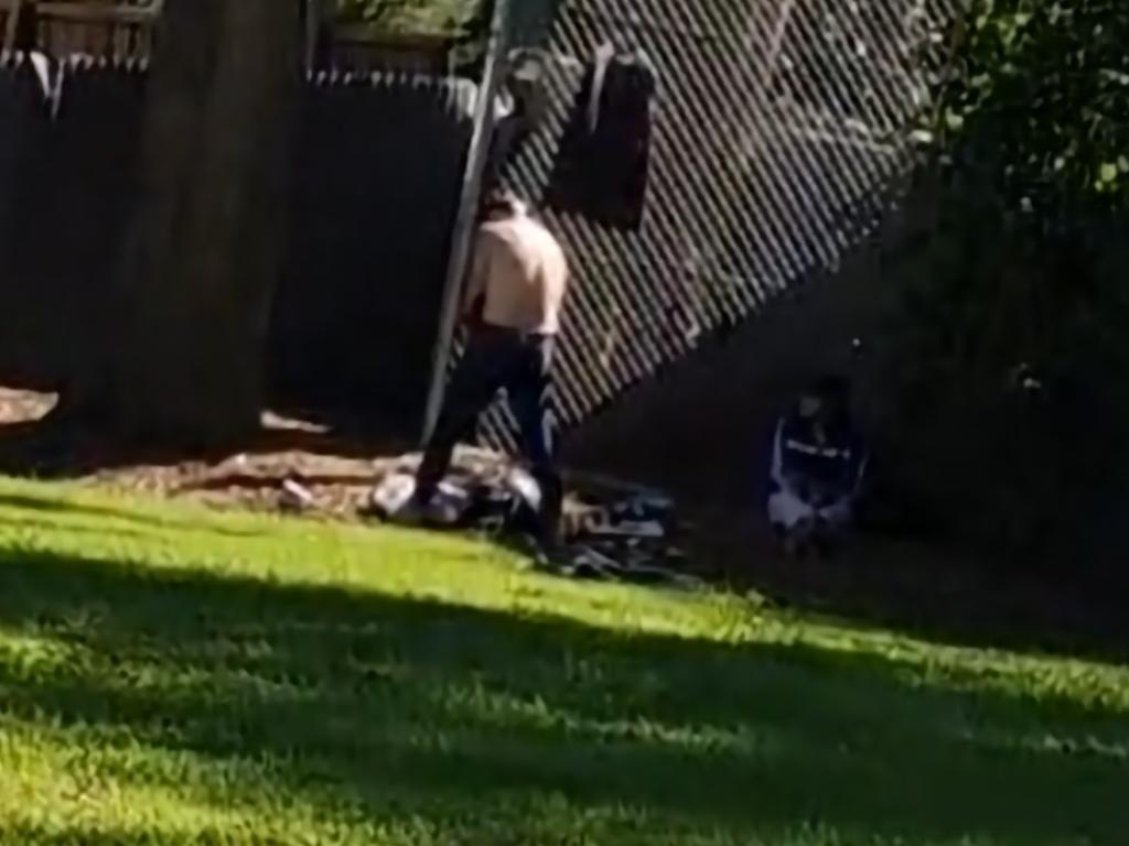 Two people in a park opposite a children’s adventure playground on Monday.