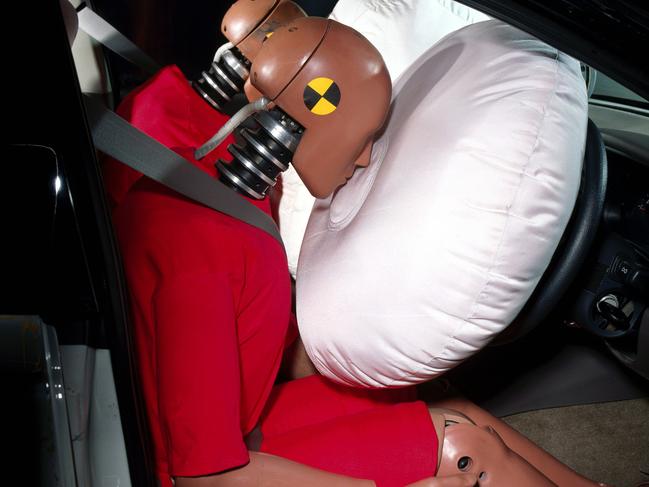 A Holden passenger airbag deploying simultaneously with driver's airbag in crash test dummy safety research experiment.