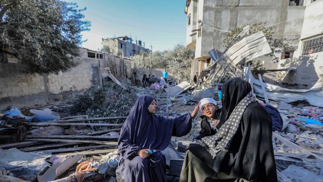 Palestinians inspect the area after their homes were destroyed by Israeli strikes.