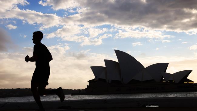 A morning jogger runs under cloudy skies through Sydney’s Circular Quay. Picture: Damian Shaw