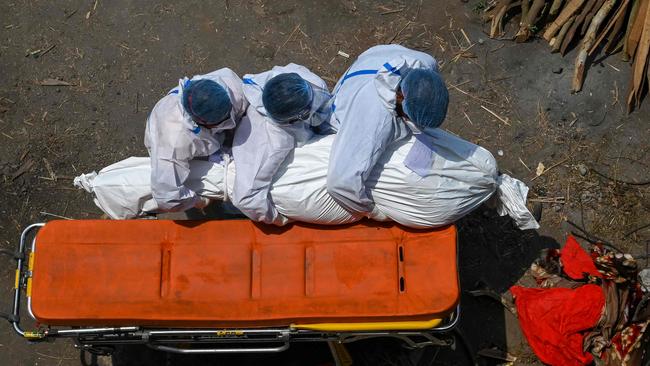 Family members and ambulance workers in PPE carry the body of a victim who died of the Covid-19 coronavirus at a cremation ground in New Delhi.