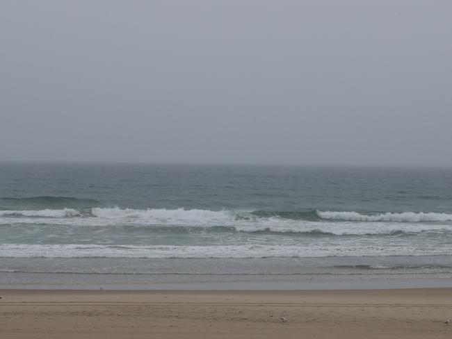 Surfers Paradise streets and beaches were deserted as a wet weather system hovered over the Gold Coast. South Australian holidaymakers including Sam McTaggart and Eddie New from Mt Gambier, try to make the best of a bad lot by heading to the beach despite the rain.  Picture Glenn Hampson