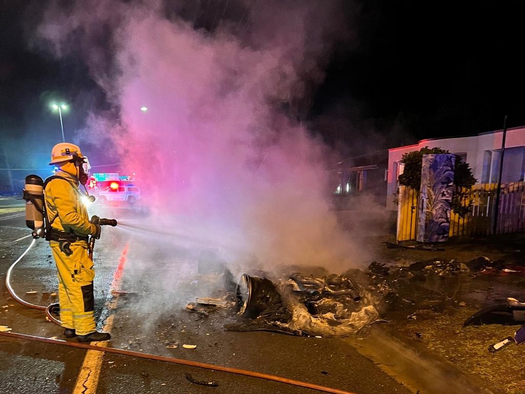 A firefighter douses the smouldering remains in water.