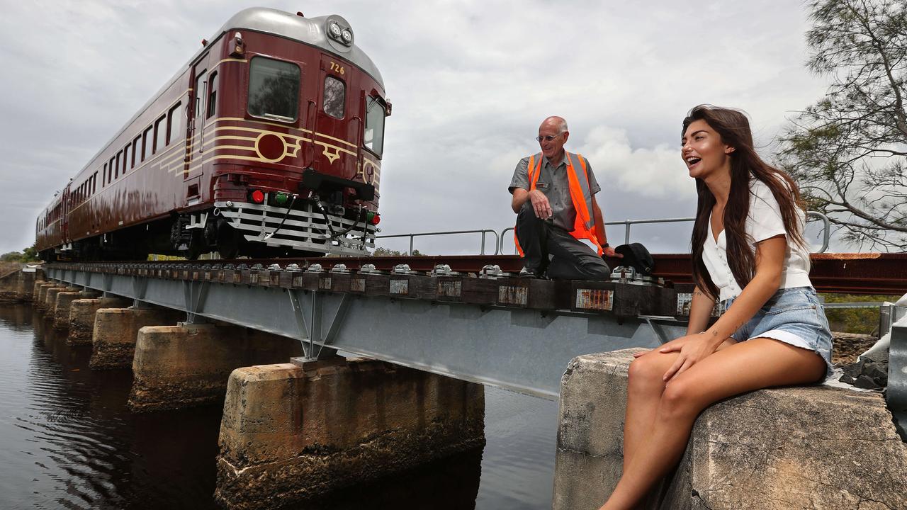 30/11/2017: A 1947 railcar converted to electric and solar power, stopped and at rest during a test run, as train driver Robert Jarvis chats with local Coco Allen, 22, who as a child played here on the old disused railway bridge over the Belongil Creek, is excited for the town to have a train once again in Byron Bay, NSW. The not for profit Byron Bay Railroad Co. has been set up to ferry passengers from the town centre to nearby northern beaches, and has become the worlds first "solar powered" train in an effort to appease local green concerns, using the existing, but closed, rail corridor. Lyndon Mechielsen/The Australian