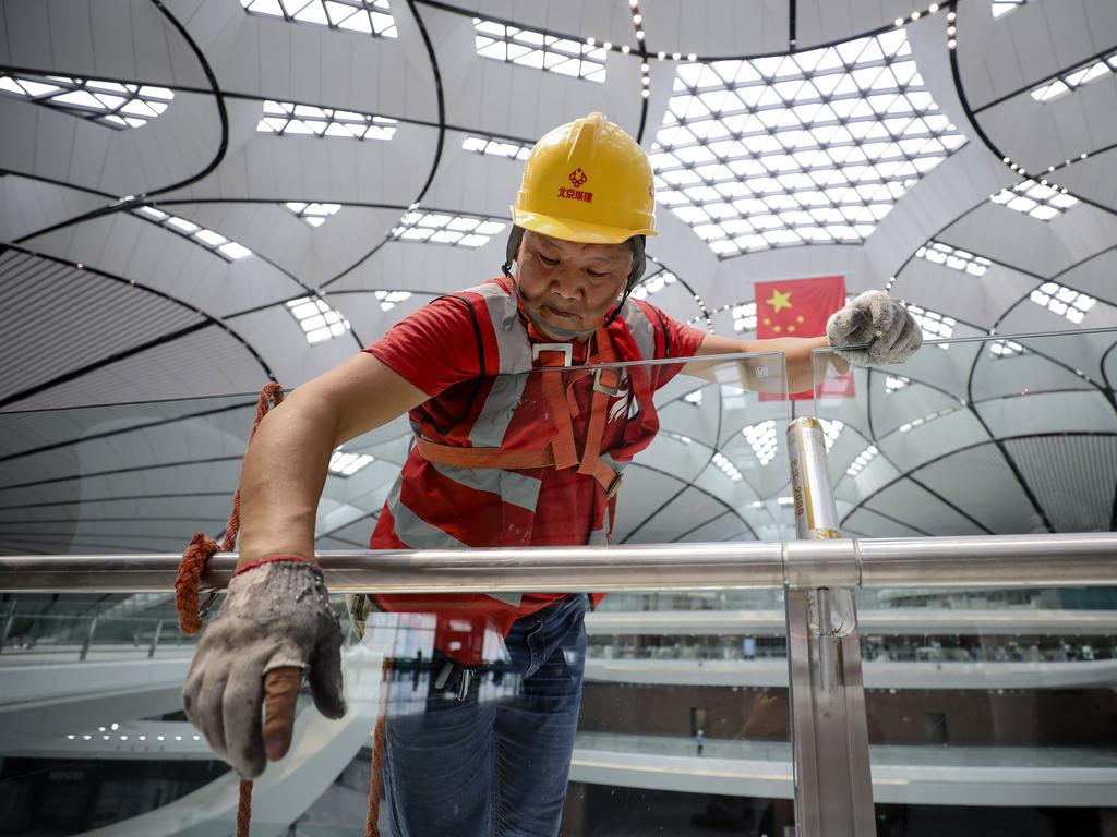 A worker cleans glass in the terminal building before its opening. Picture: STR/AFP