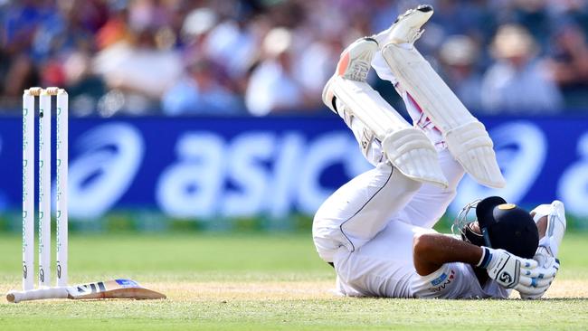 Sri Lanka’s Dimuth Karunaratne falls to the ground after being hit by a delivery from Australia’s Pat Cummins. Picture: AFP