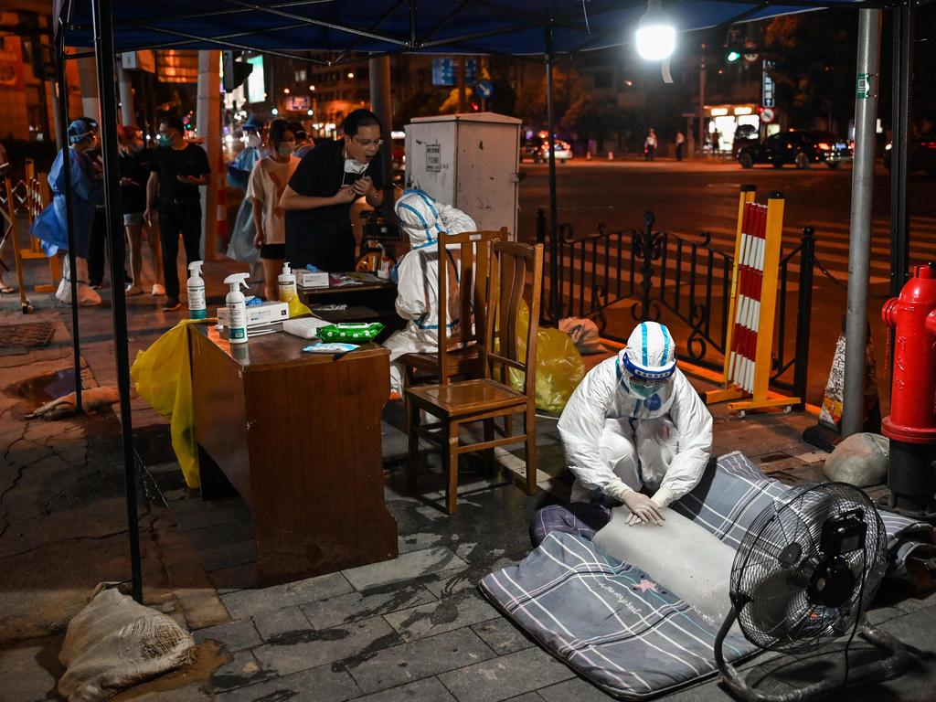 A health worker puts her hands on a block of ice in front of a fan to cool off at a coronavirus testing station in the Huangpu district of Shanghai. Picture: AFP