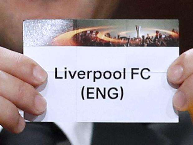 Swiss former football player Alexander Frei shows the name of Liverpool FC football club during the UEFA Europa League group stage draw ceremony on August 28, 2015 in Monaco. AFP PHOTO / VALERY HACHE