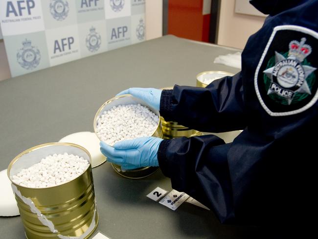 An Australian Federal Police officer examining cans used in the Tomato Tins-importation sting.