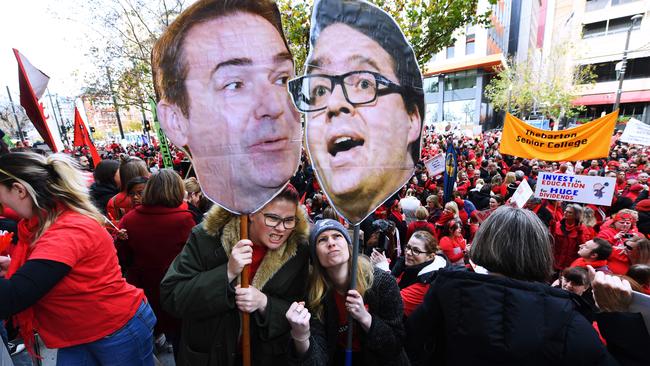 Ann Clarke and Phoebe Gunn hold head posters of Premier Steven Marshall and Education Minister John Gardner during today’s rally. Picture: AAP/Mark Brake