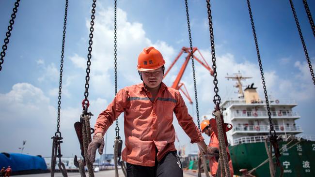 This photo taken on August 7, 2018 shows workers unloading bags of chemicals at a port in Zhangjiagang in China's eastern Jiangsu province. China's trade surplus with the United States eased in July, when President Donald Trump imposed stiff tariffs on billions of dollars worth of Chinese goods in a showdown between the world's two biggest economies. The figures on August 8 come as the two exchange threats of further measures, which have fuelled fears of a trade war many observers warn could hammer global business. / AFP PHOTO / Johannes EISELE