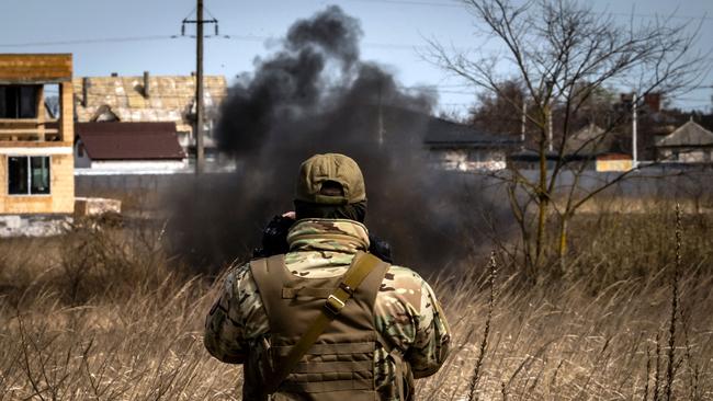 A member of a bomb disposal bomb squad looks at smoke as he works in minefield near Kyiv in 2022. Picture: AFP