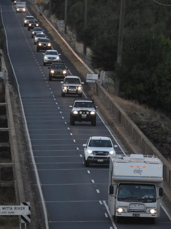 Convoy leave Corryong fires under CFA protection across the Hume River. Picture: Tony Gough