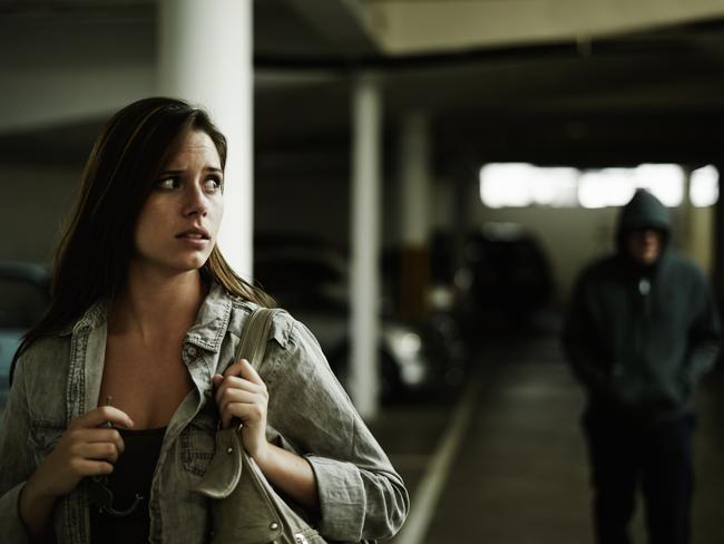 A terrified young woman in an underground parking garage being followed by a sinister man