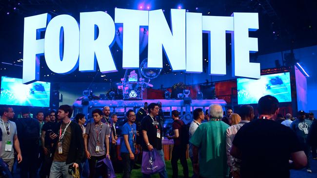 (FILES) This file photo taken on June 12, 2018 shows people crowding the display area for the survival game Fortnite at the 24th Electronic Expo, or E3 2018, in Los Angeles, where hardware manufacturers, software developers and the video game industry present their new games. - Fortnite's popularity took off last year after the release of a free "battle royale" version that lets up to 100 players vie to be the last character standing on ever-shrinking terrain. Dropped onto the battlefield with nothing, players have to scrounge for weapons as the fight for survival begins. (Photo by Frederic J. BROWN / AFP)