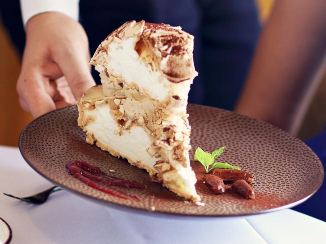 A woman being served a slice of cake at a restaurant. Picture: iStock.