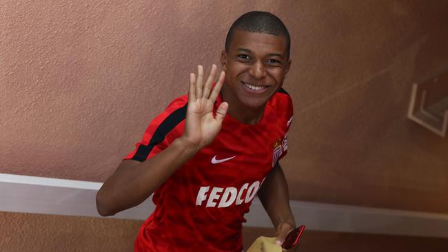 Monaco's French forward Kylian Mbappe waves as he enters the dressing room.