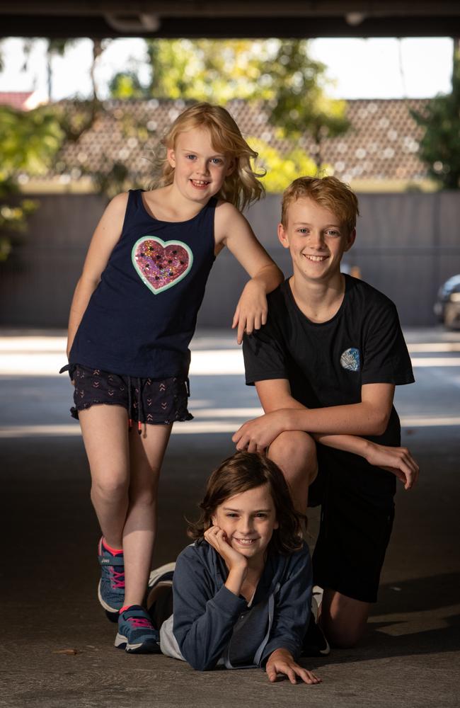 Samuel Whiley, 10, (centre) who got crushed under an industrial garage door and was saved by his siblings Jessica, 7, and William, 12. Pictured in the carpark with the open garage door behind them. Picture: Julian Andrews