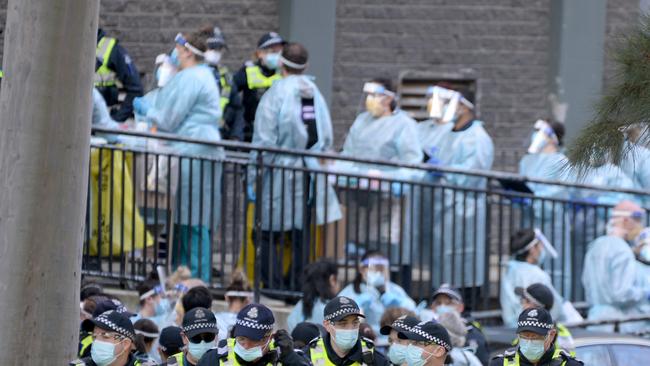 Police and healthcare workers prepare to enter one of the towers at the North Melbourne public housing estate. Picture: Andrew Henshaw