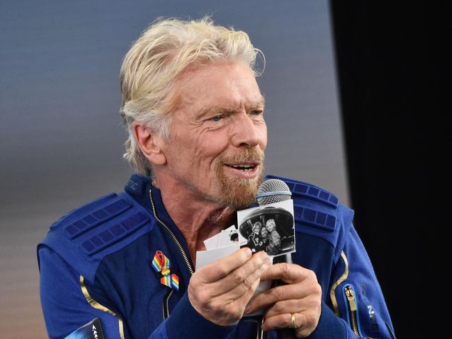 Sir Richard Branson holds up photos that he brought with him into space, as he speaks after flying into space aboard a Virgin Galactic vessel, a voyage he described as the "experience of a lifetime" -- and one he hopes will usher in an era of lucrative space tourism at Spaceport America, near Truth and Consequences, New Mexico on July 11, 2021. - "Congratulations to all our wonderful team at Virgin Galactic for 17 years of hard, hard work to get us this far," he said during a live feed as the VSS Unity spaceship glided back to Spaceport America in New Mexico.It reached a peak altitude of around 53 miles (85 kilometers) -- beyond the boundary of space, according to the United States -- allowing the passengers to experience weightlessness and admire the Earth's curvature.The trip proceeded without drama, and touchdown occurred at around 9:40 am Mountain Time (1540 GMT), about an hour after take-off. (Photo by Patrick T. FALLON / AFP)