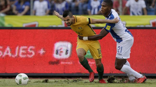 Australia’s Aziz Behich fights Honduras’s Brayan Beckeles and the Estadio Olimpico pitch.