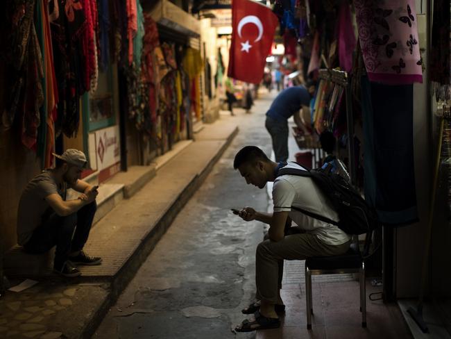 Sellers wait for customers as they look at their phones in central Istanbul, Monday, July 18, 2016. Warplanes patrolled Turkey's skies days after a failed coup, officials said Monday, in a sign that authorities feared that the threat against the government was not yet over. (AP Photo/Emilio Morenatti)