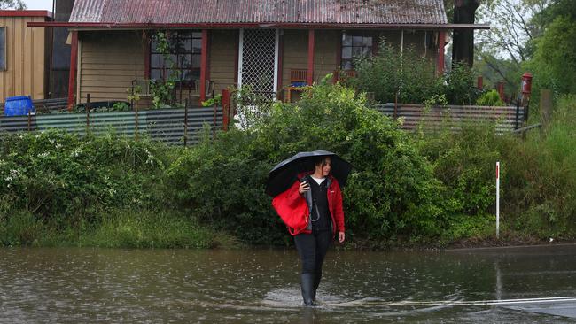 A woman stands outside a flood-affected home along the Hawkesbury River in Windsor on Monday. Picture: Getty Images