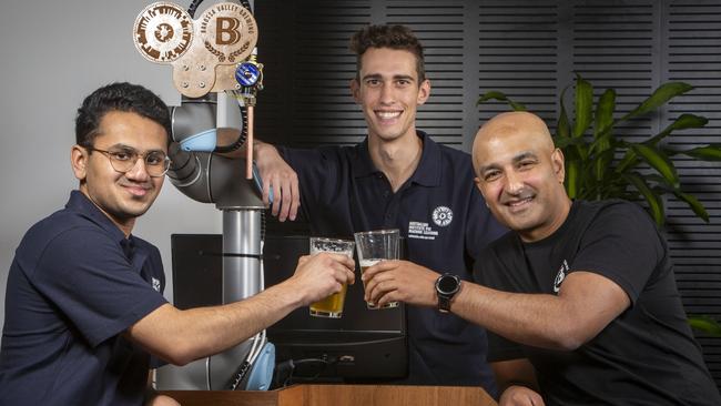 Computer scientists Josh Vira (left) and Christopher Fusco (back) pour a beer for Barossa Valley Brewing chief Denham D'Silva (right) at the Australian Institute for Machine Learning at Lot Fourteen, SA. Picture: Emma Brasier