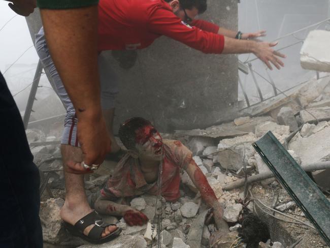 Syrian men remove a victim from the rubble of a building following a reported air strike on the rebel-held Bustan al-Qasr neighbourhood in Aleppo. Picture: Ameer Alhalbi.