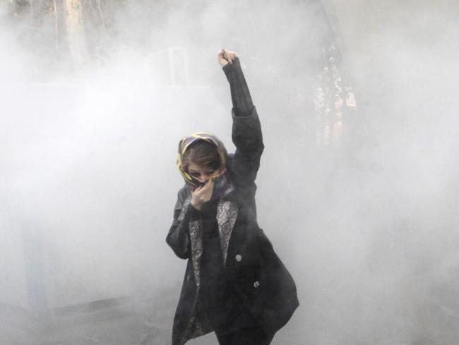 In this photo taken by an individual not employed by the Associated Press and obtained by the AP outside Iran, a university student attends a protest inside Tehran University while a smoke grenade is thrown by anti-riot Iranian police, in Tehran, Iran, Saturday, Dec. 30, 2017. A wave of spontaneous protests over Iran's weak economy swept into Tehran on Saturday, with college students and others chanting against the government just hours after hard-liners held their own rally in support of the Islamic Republic's clerical establishment. (AP Photo)