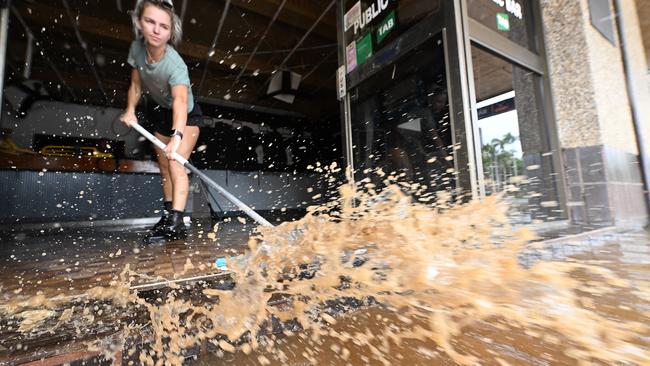 Wading through the now receding flood waters, Laani Winkler 25, helps friend Kylie Gilmore clean her flood ravaged pub in the central business district, for the second time in weeks at Lismore. Picture: Lyndon Mechielsen.