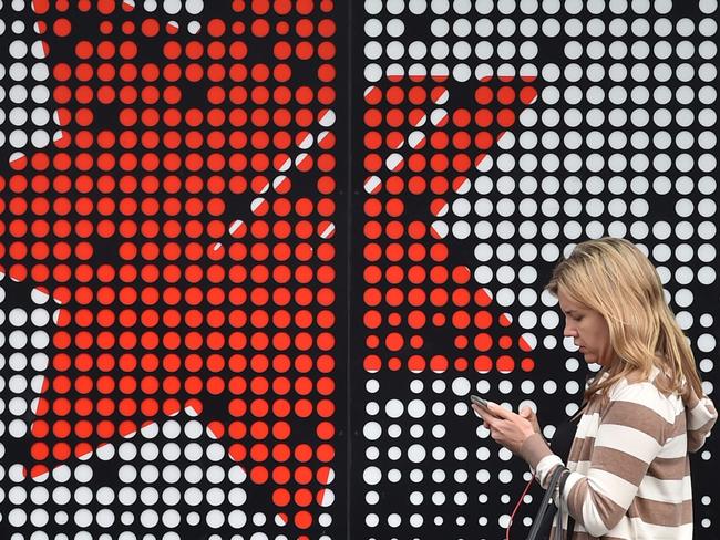 (FILES) In this file photo taken on November 1, 2017 a woman walks past a National Australia Bank (NAB) branch in Sydney. National Australia Bank announced plans to sell down its wealth management arm on May 3, 2018 as it continues to offload assets to simplify its business.  / AFP PHOTO / PETER PARKS