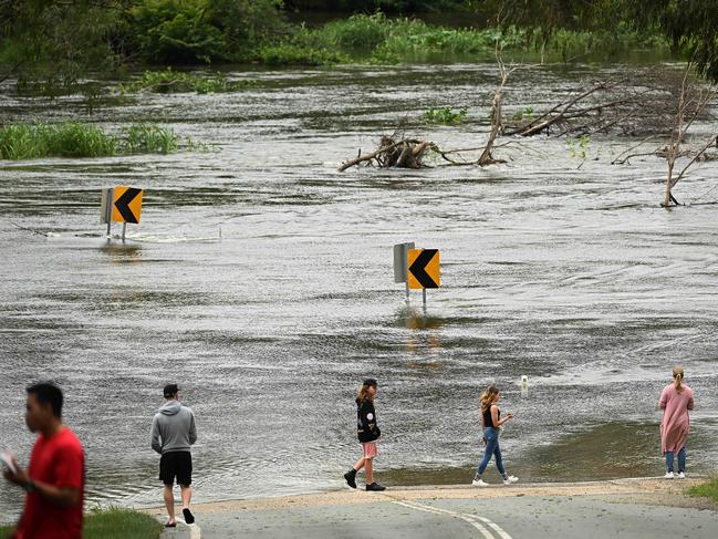 Locals turn out to see Youngs Crossing Rd flooded and closed after heavy rain across the region. Picture: .Lyndon Mechielsen