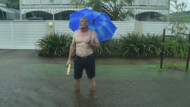 Heavy rain lashes Townsville causing flash flooding. Pimlico resident John McGuire tries to get cars to slow down in the flooded road outside his home in Palmerston Street. Picture: Evan Morgan