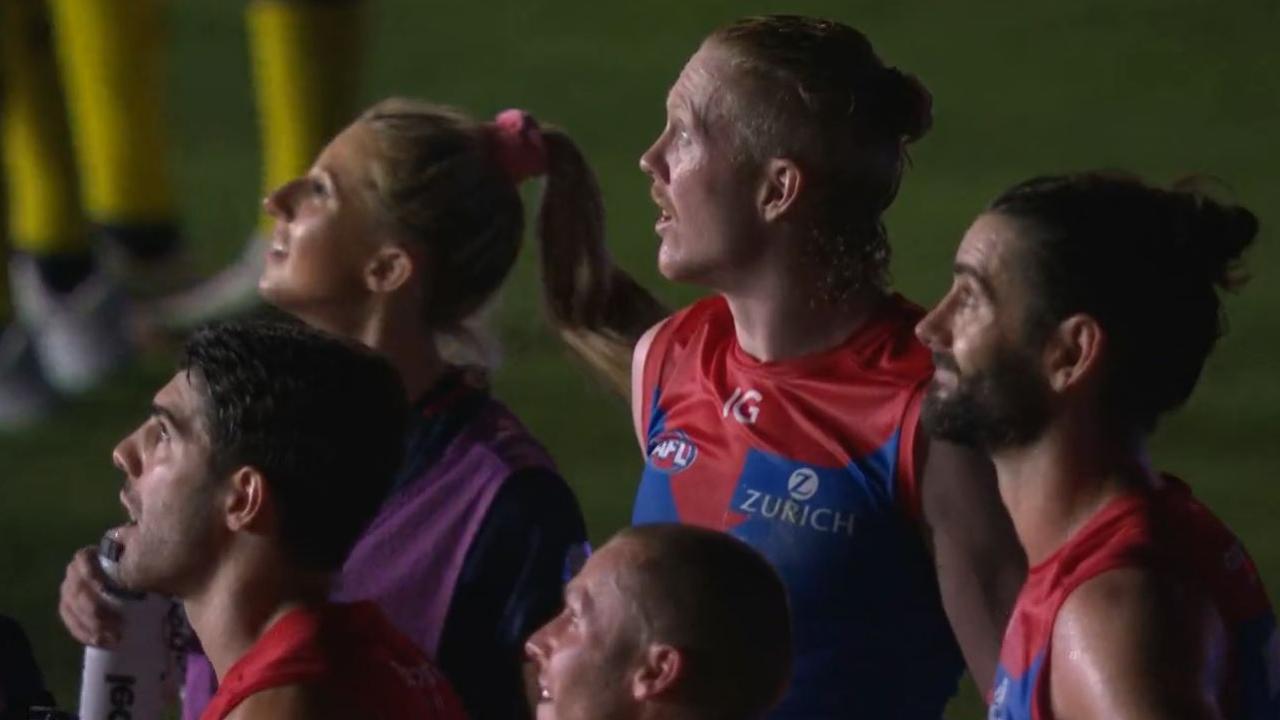 Melbourne players look on as the lights go out at the Gabba. Picture: AFL