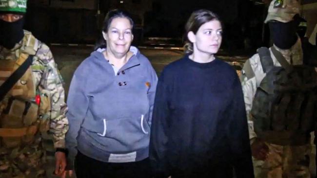 An image grab from a handout video released by the Hamas Media Office shows Hamas fighters accompanying newly released Israeli hostages Shiri Weiss (left) and her daughter Noga, to a Red Cross vehicle in the Gaza Strip early on Sunday. Picture: Hamas Media Office/AFP