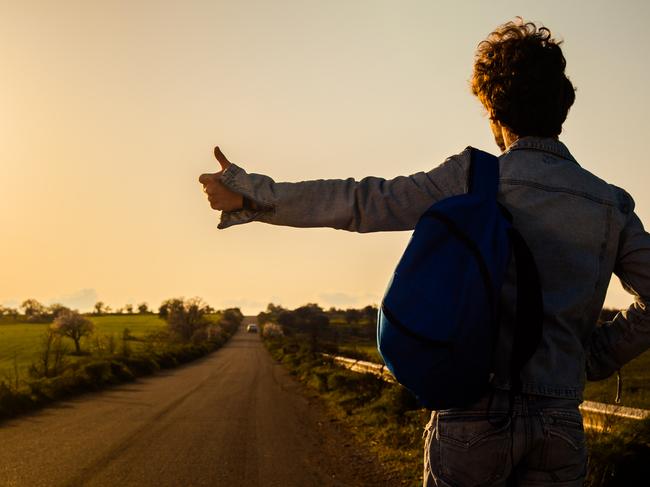 Young Man Hitchhiking on a Country Road