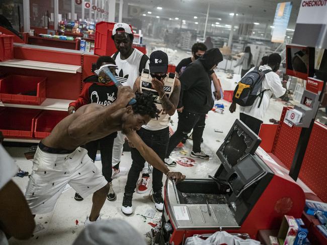 A looter uses a claw hammer as he tries to break in to a cash register at a Target store in Minneapolis. Picture: AP