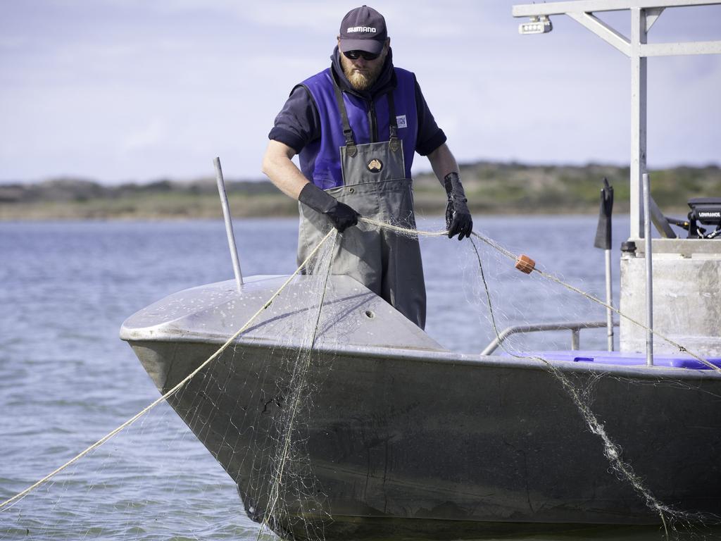 A fisherman inspects his damaged net.